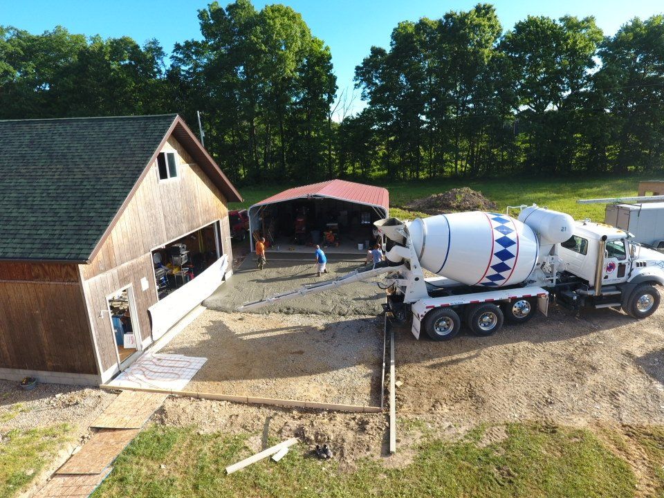 An aerial view of a concrete mixer truck in front of a garage