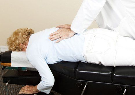 Chiropractor adjusting a senior woman's back.