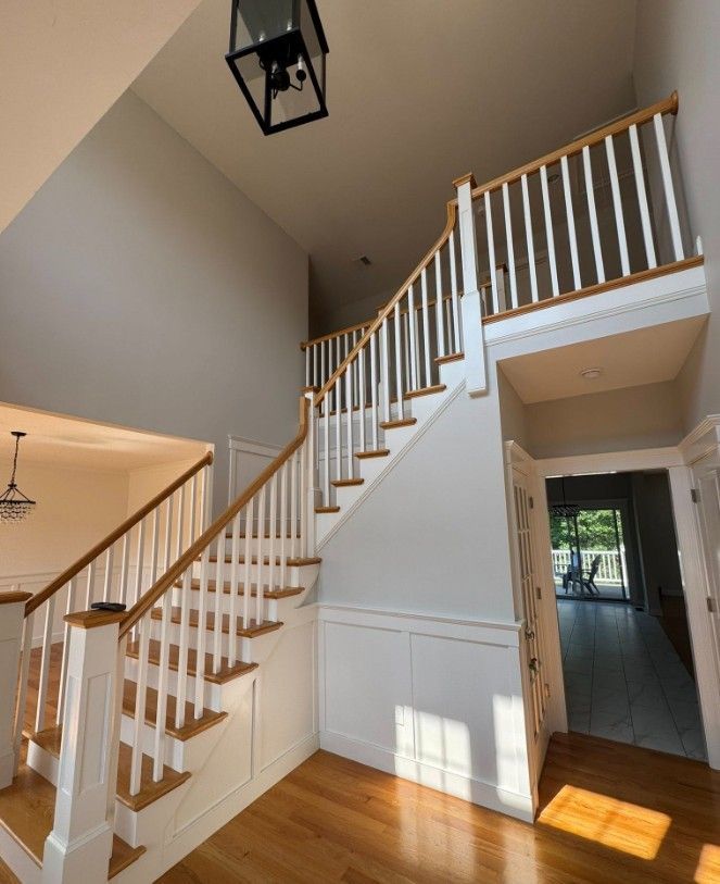 Interior view of a staircase with wood steps, white balusters, and a wooden handrail.
