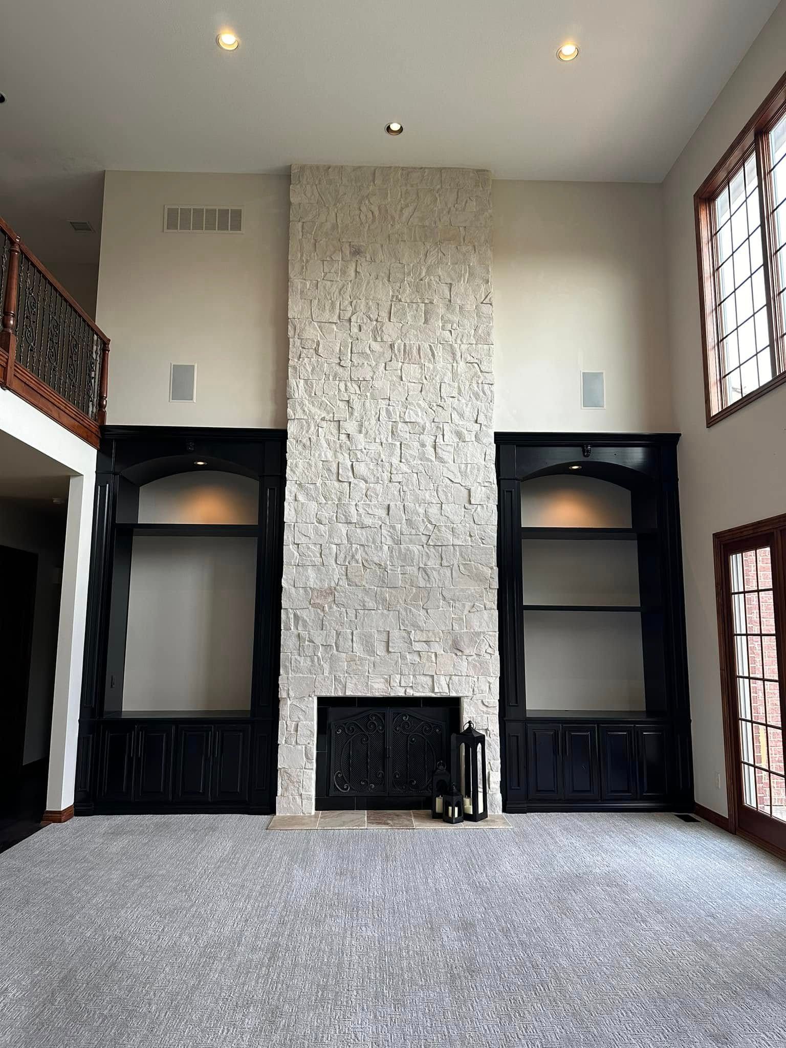 Painted black built in cupboards on each side of a stone wall with fireplace in Urbandale, Iowa.