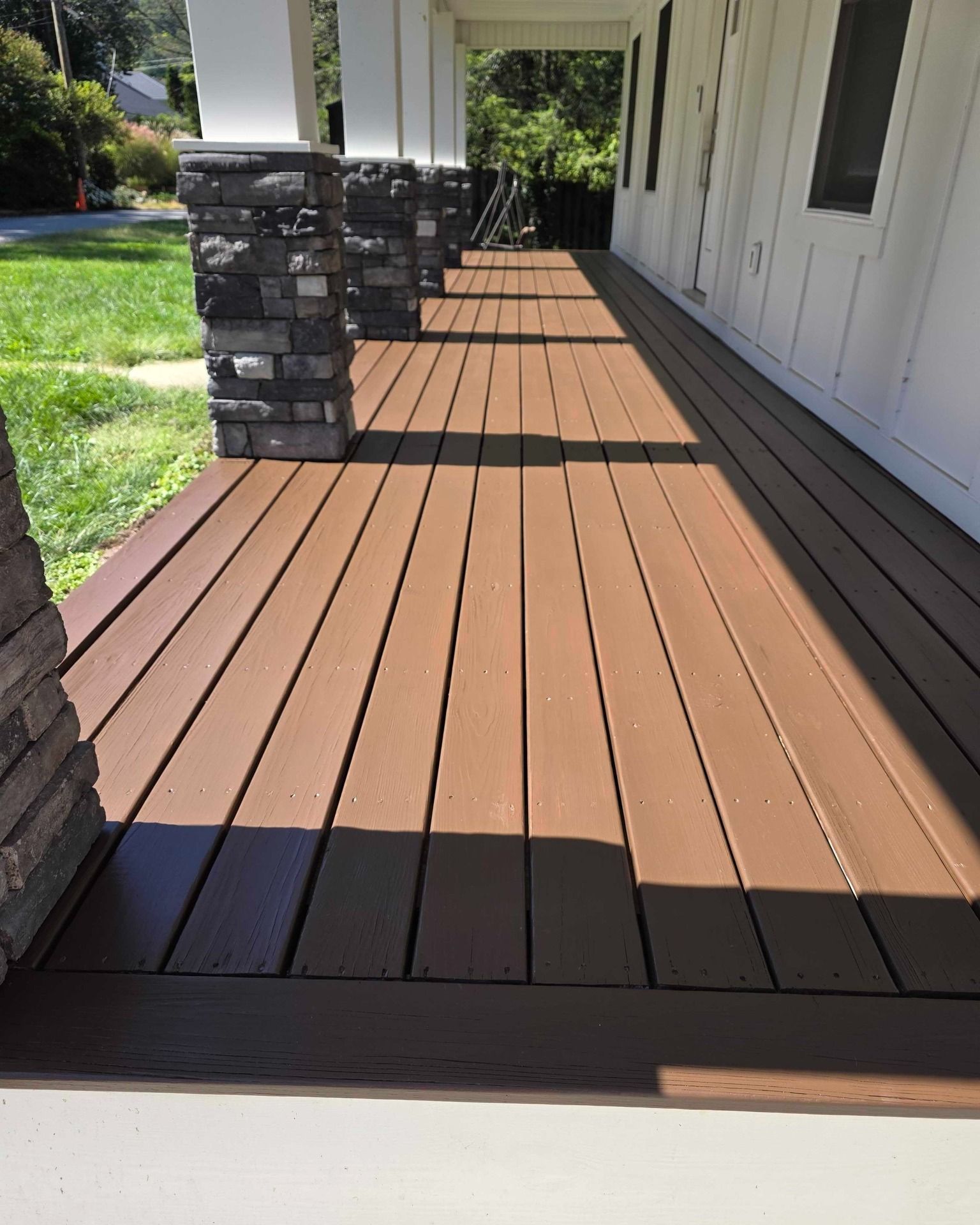 Stained brown deck with brick and white pillars in Grimes, Iowa.