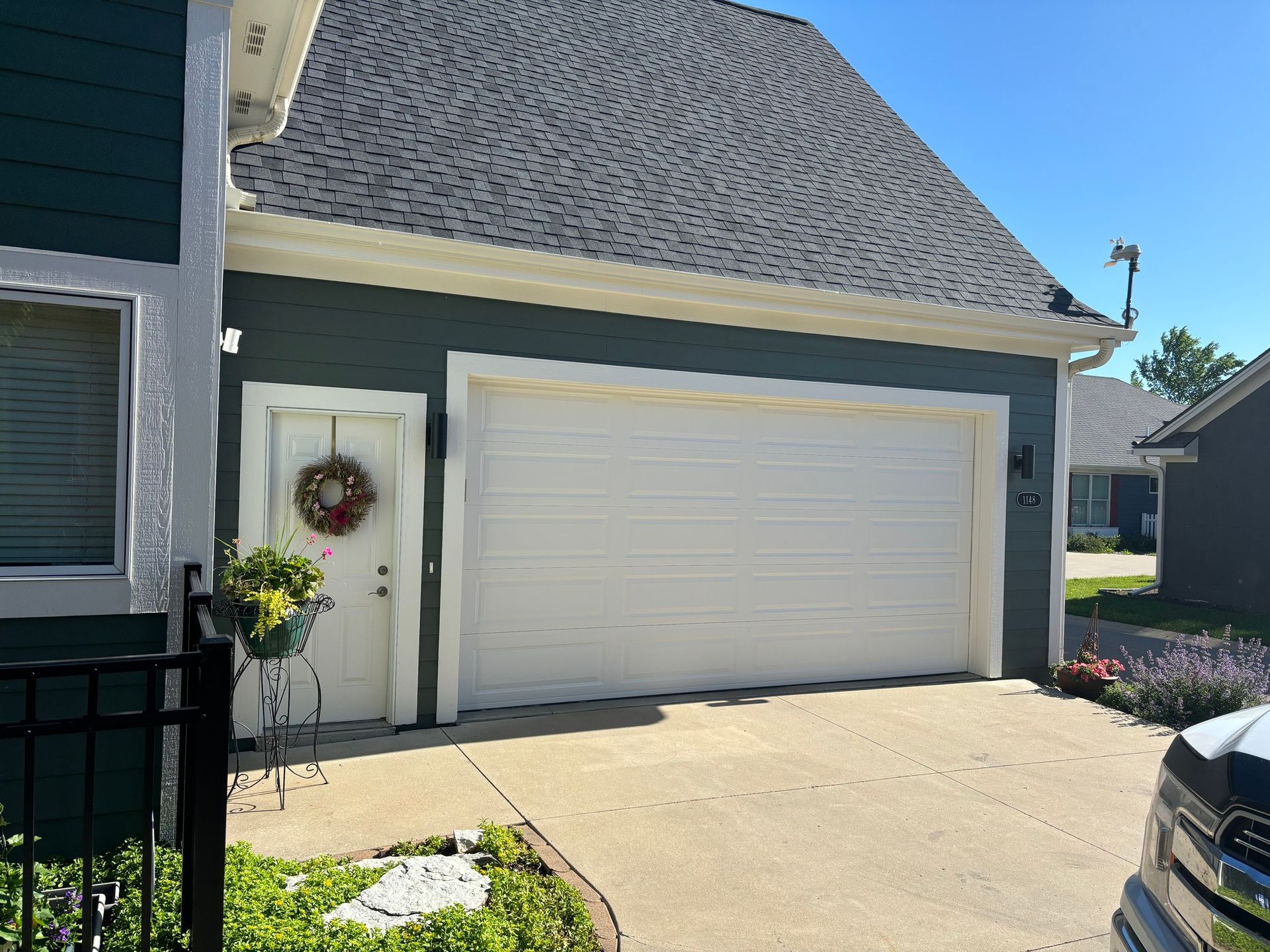 Painted blue garage with white garage doors, wreath on entrance door in Urbandale, Iowa. 