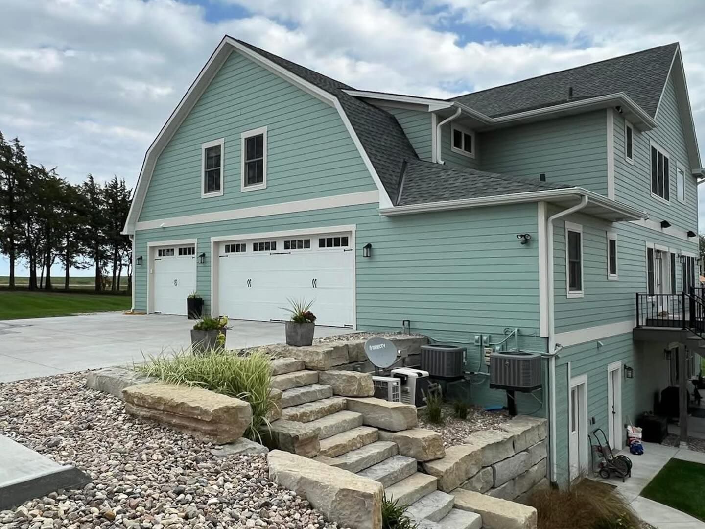 Painted Green house with cement stairs and white garage doors in Ankeny, iowa.