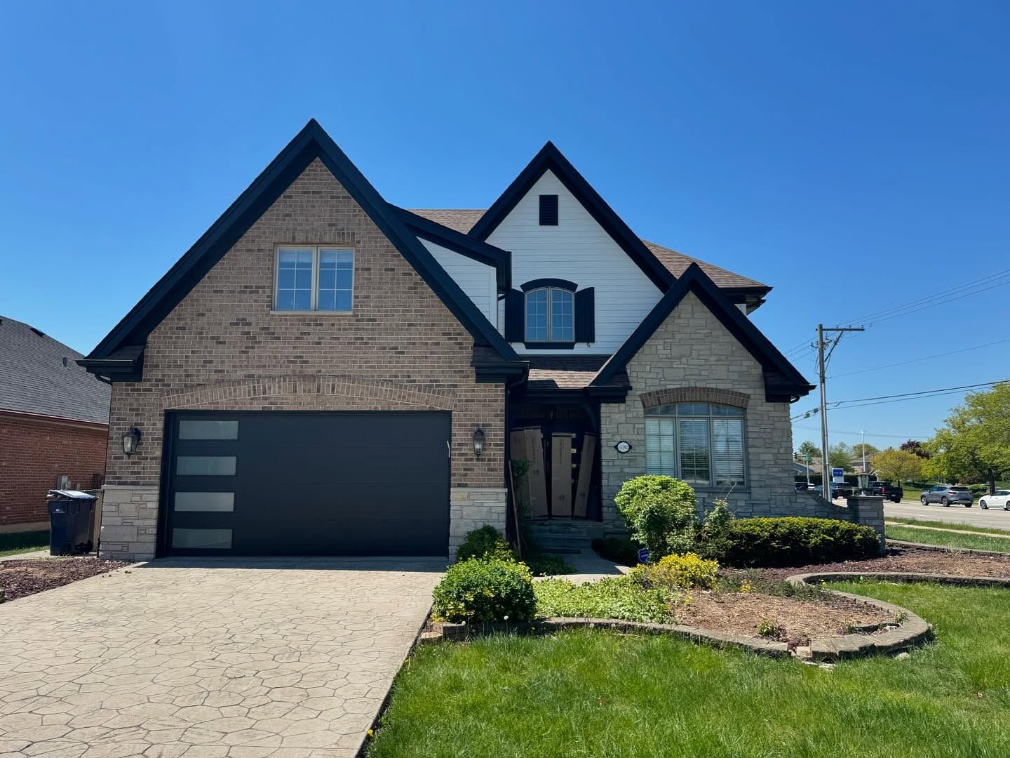 white painted siding, Tan brick house with black garage doors in Urbandale, Iowa.