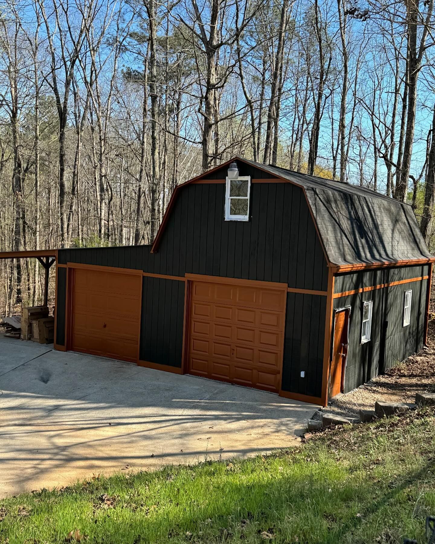 Painted Black shed with orange trim and garage doors in Johnston, Iowa.