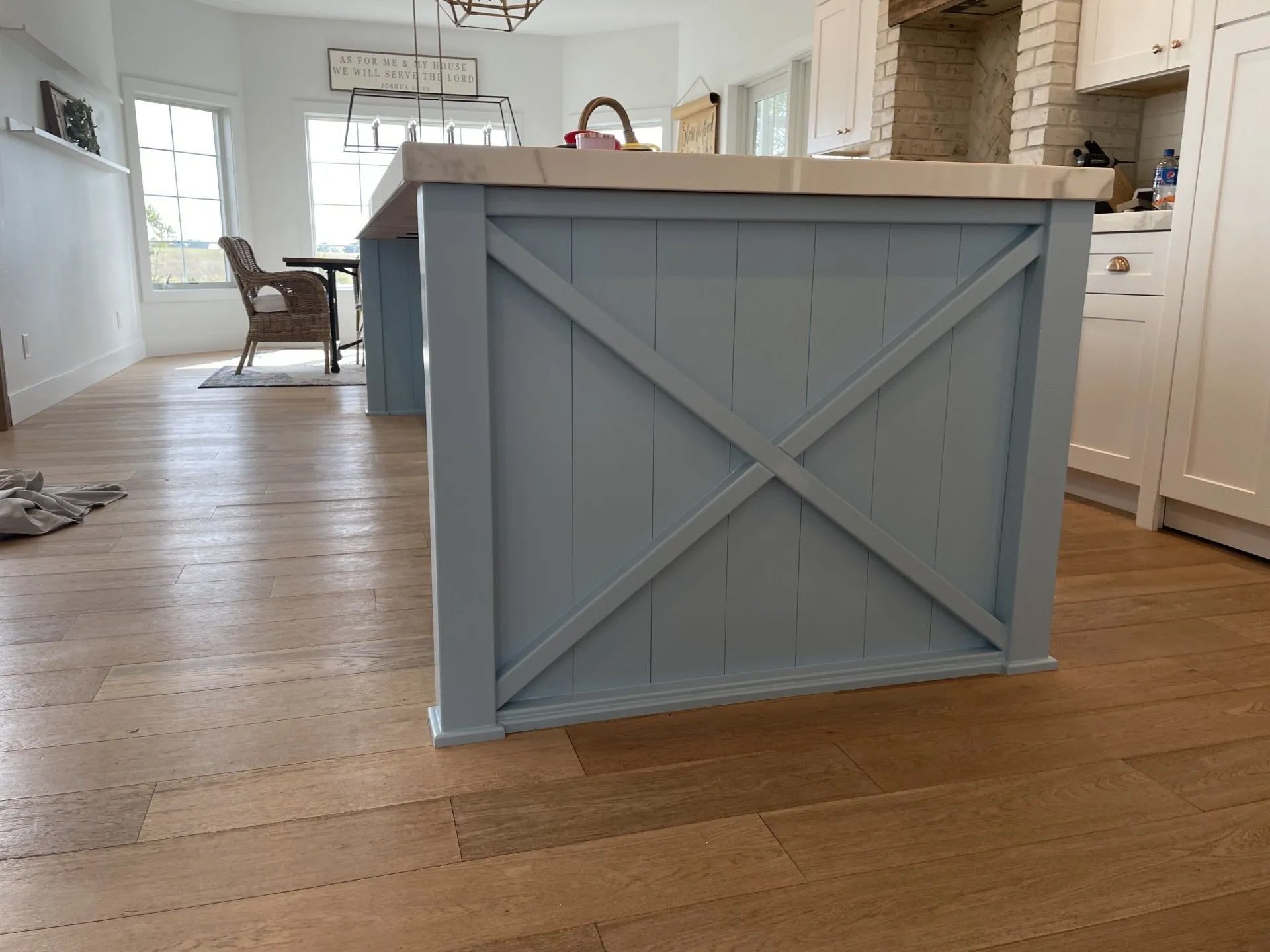 Kitchen island with blue cross-braced panels and a light countertop, set on wooden floors.