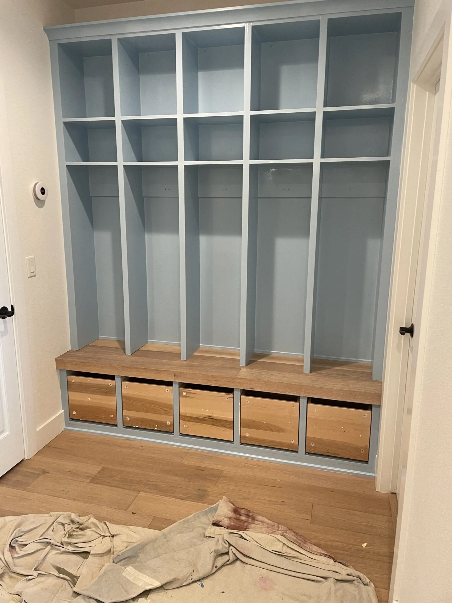 Built-in blue storage unit with open cubbies, drawers, and a wooden bench. Interior room.