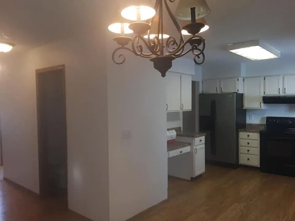 Kitchen with white cabinets, black appliances, and a chandelier.
