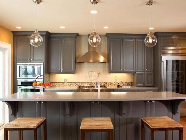 Gray kitchen with island, pendant lights, cabinets, and stools.