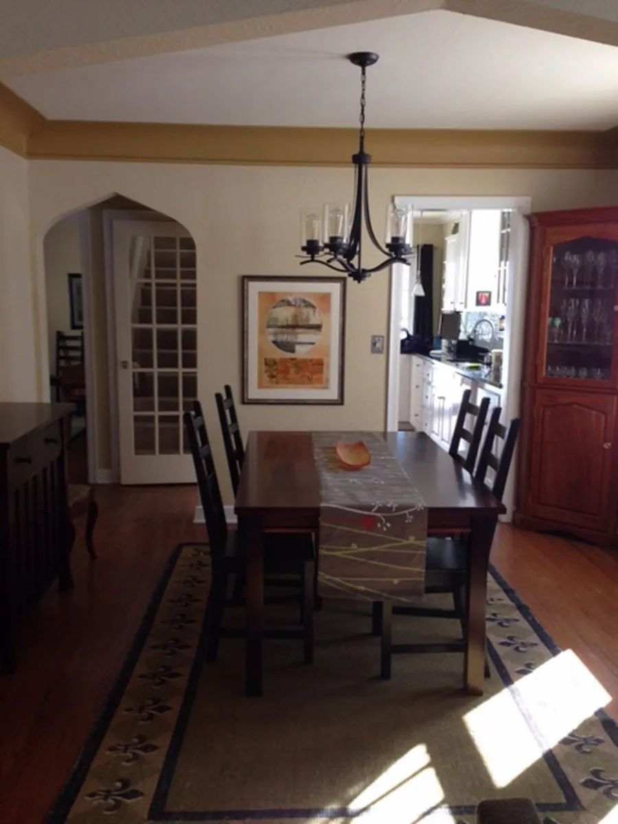 Dining room with table, chairs, chandelier, artwork, and arched doorway; warm colors.