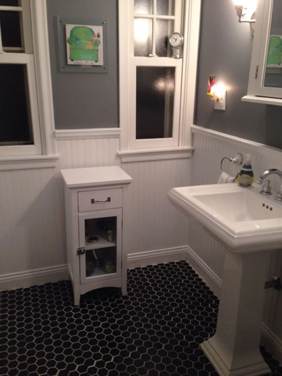 Bathroom with black hexagonal tile floor, white pedestal sink, gray walls, and white trim.
