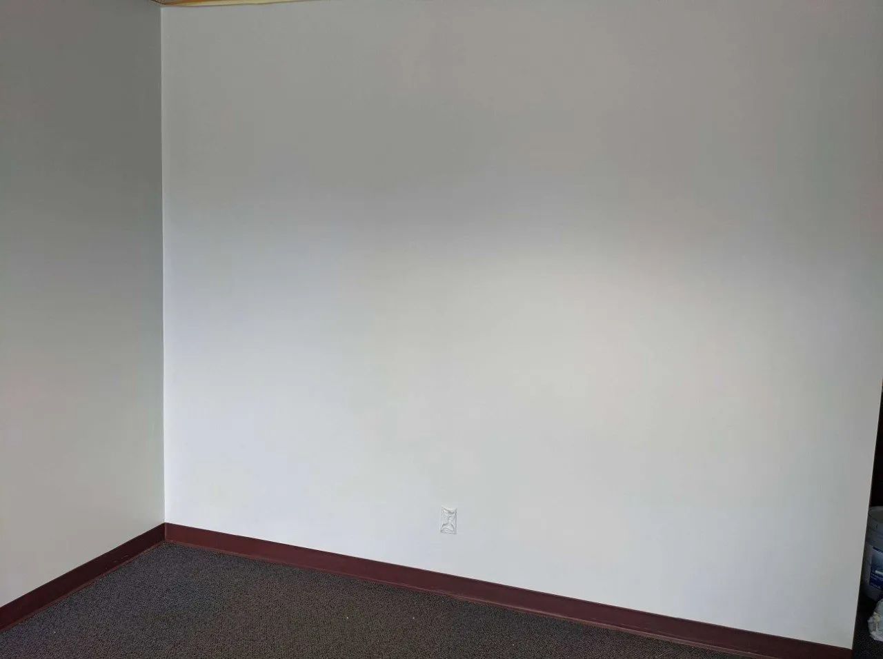 Corner of room with white walls, brown trim, and gray carpet.