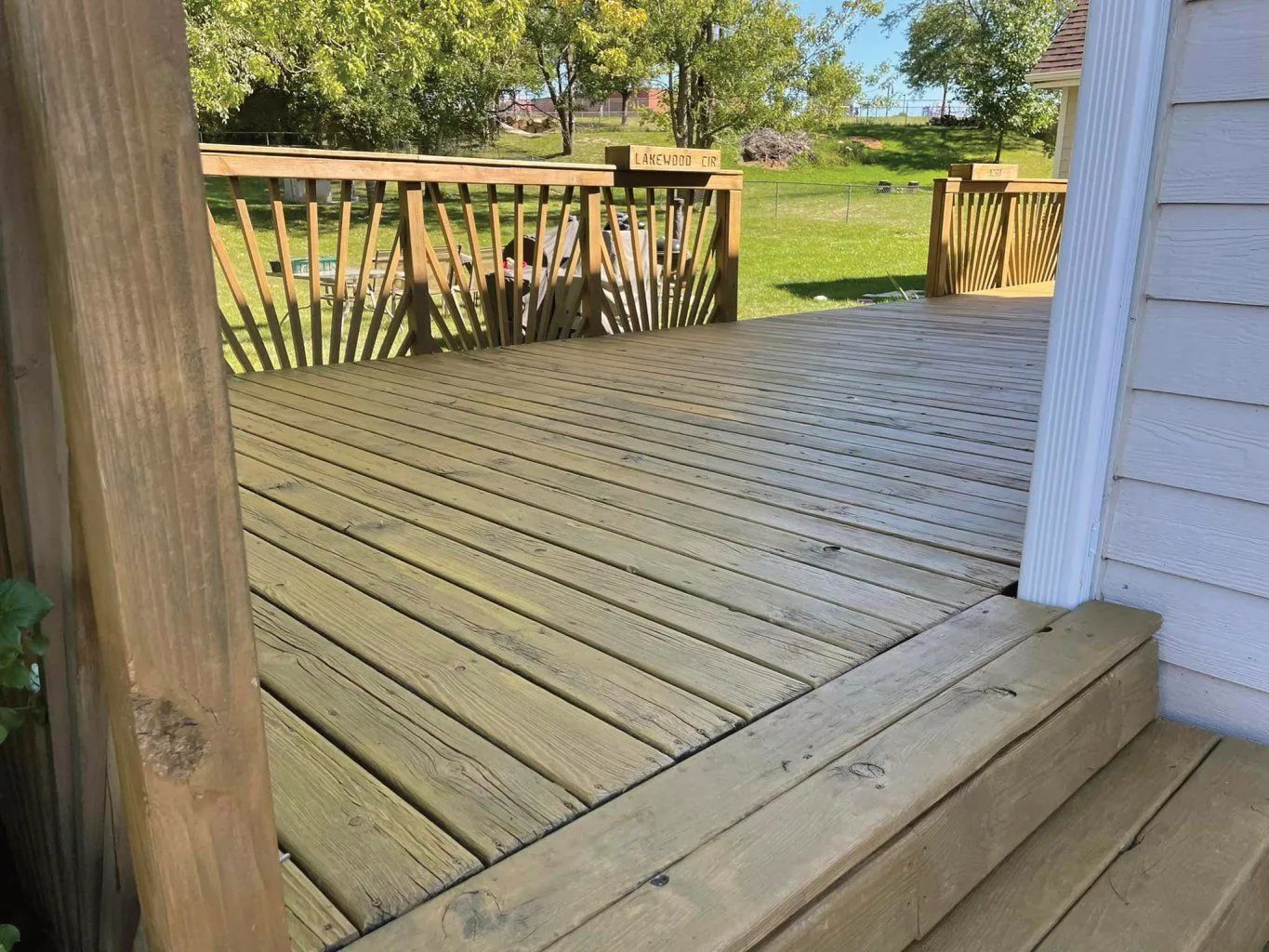 Wooden deck with railing, stairs, and view of a grassy yard.