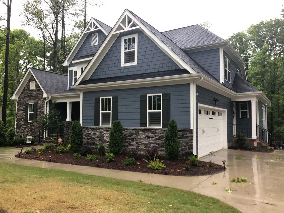Blue house with stone accents, white trim, garage, and landscaping.