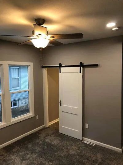 Bedroom with gray walls, a white sliding door, ceiling fan, and window.