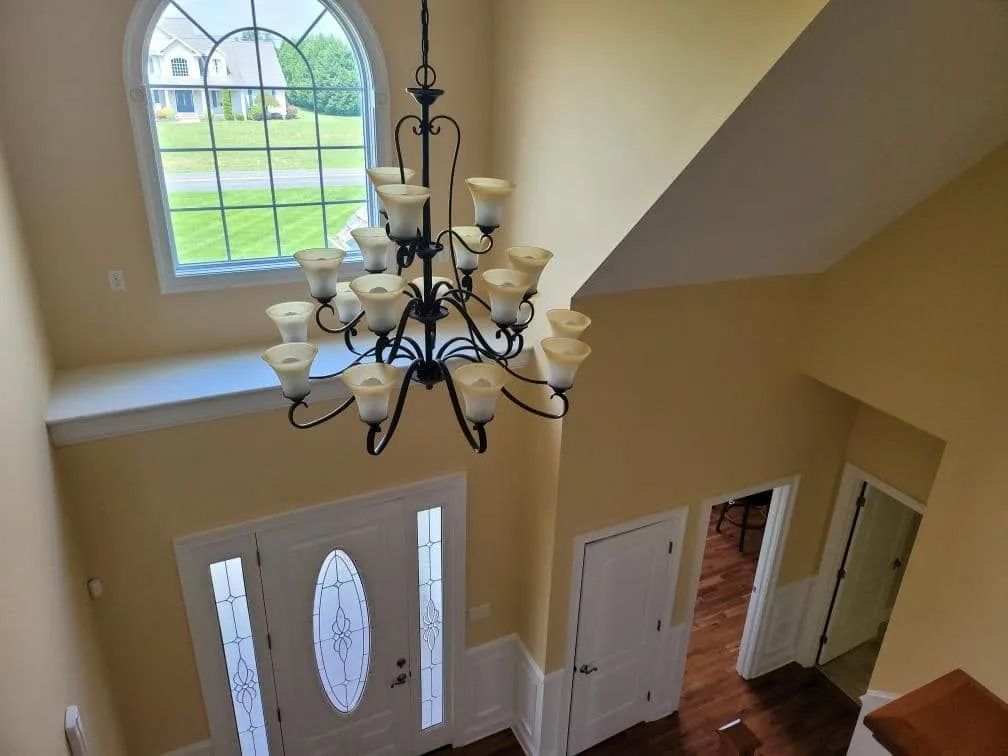Interior entryway with chandelier, window, and front door. Walls are beige.