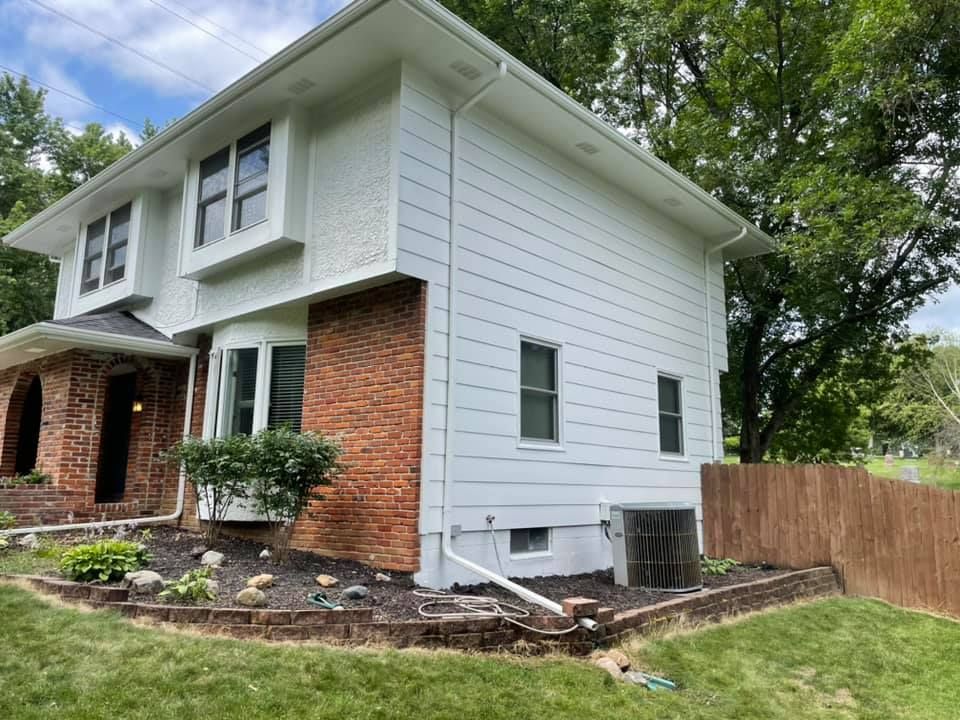 Two-story house with white siding, brick facade, and landscaping.