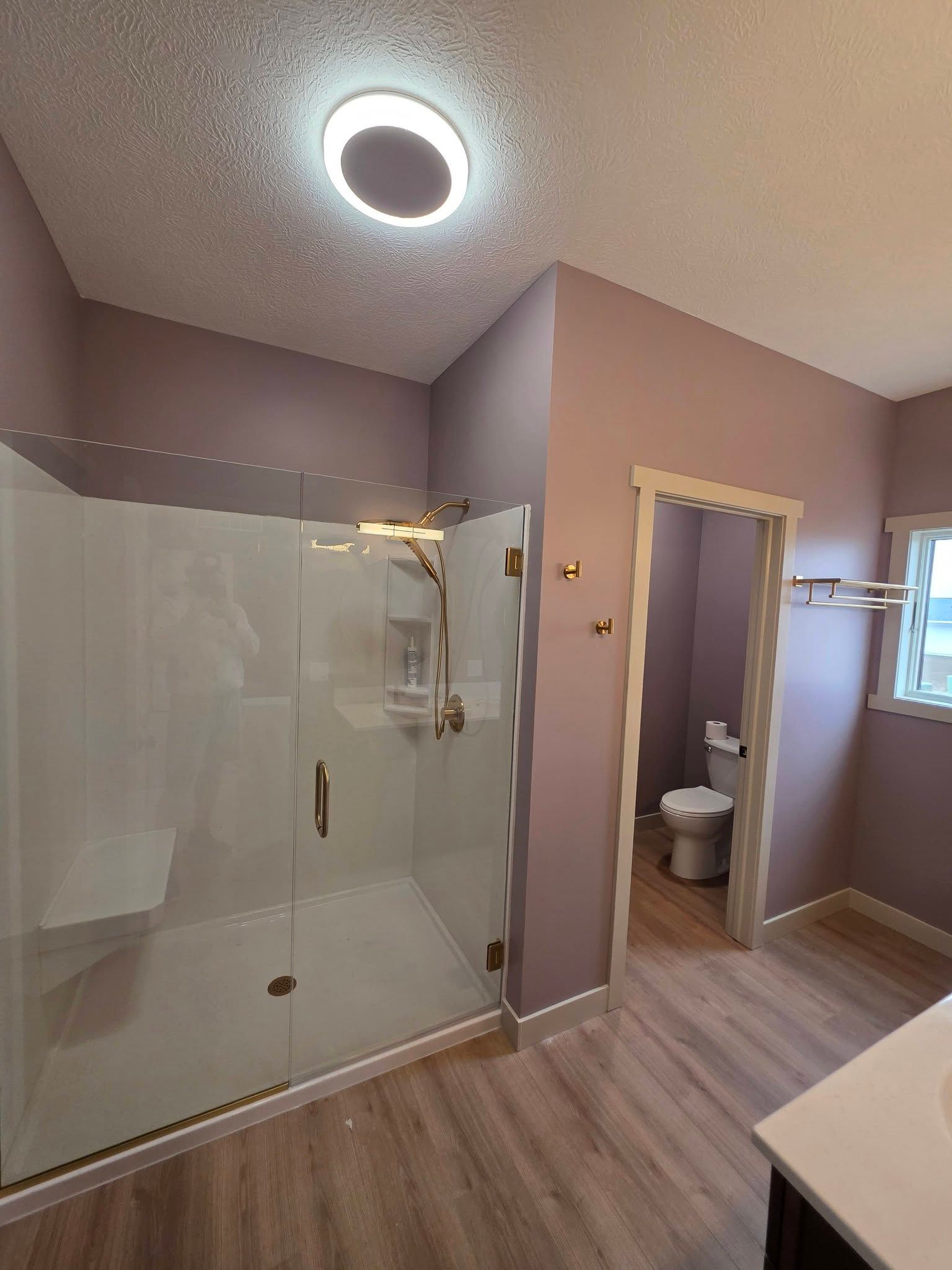 Room with green walls, dark wood floors, and a rug. It has a piano, french doors, and a window.
