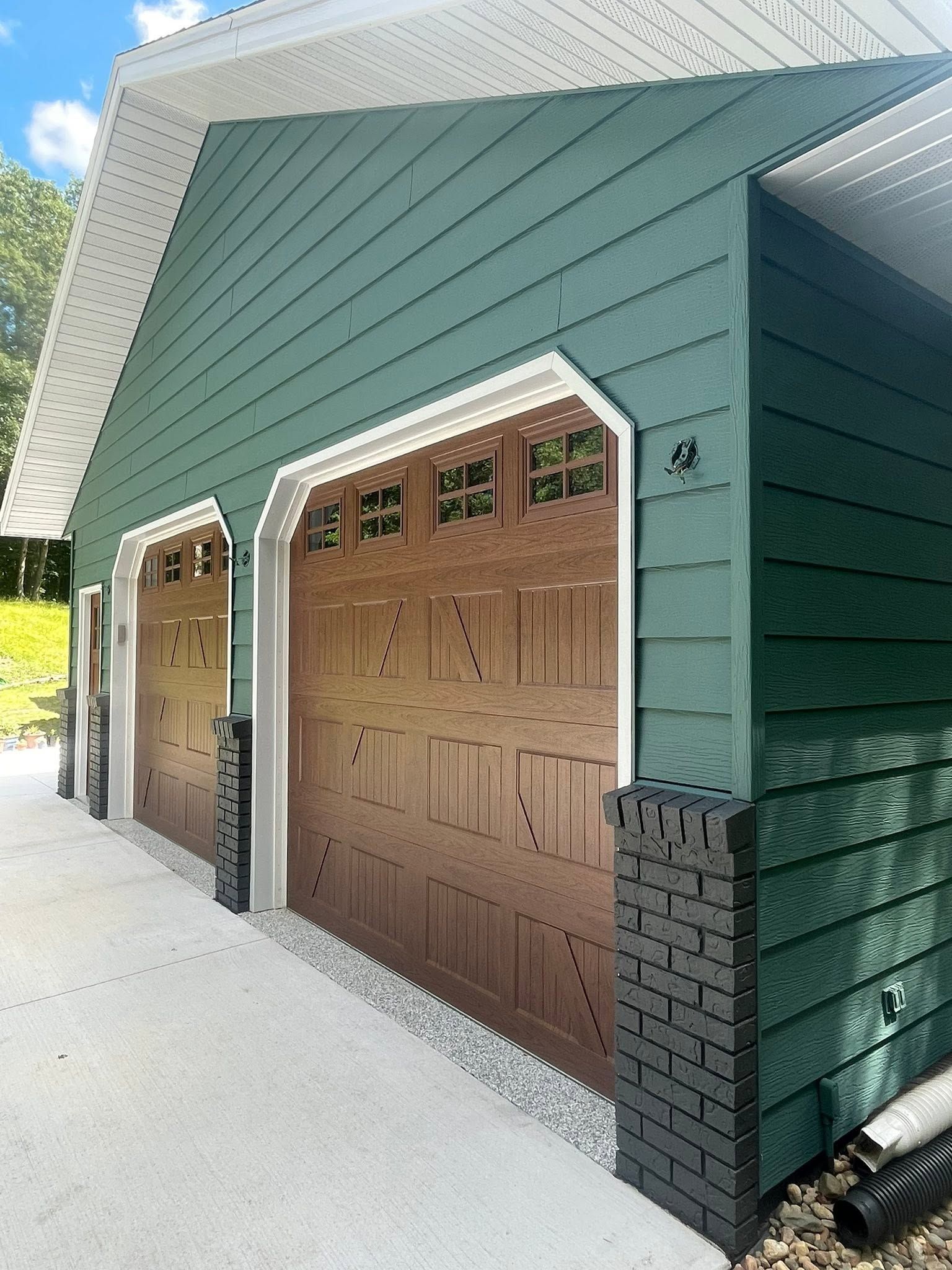 Exterior painted house green with brown garage doors in Ankeny, Iowa. 