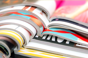 A bunch of magazines are stacked on top of each other