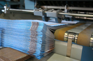 A stack of blue paper is being printed on a machine