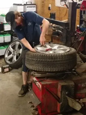 Mechanic mounting a tire on a wheel in an auto repair shop