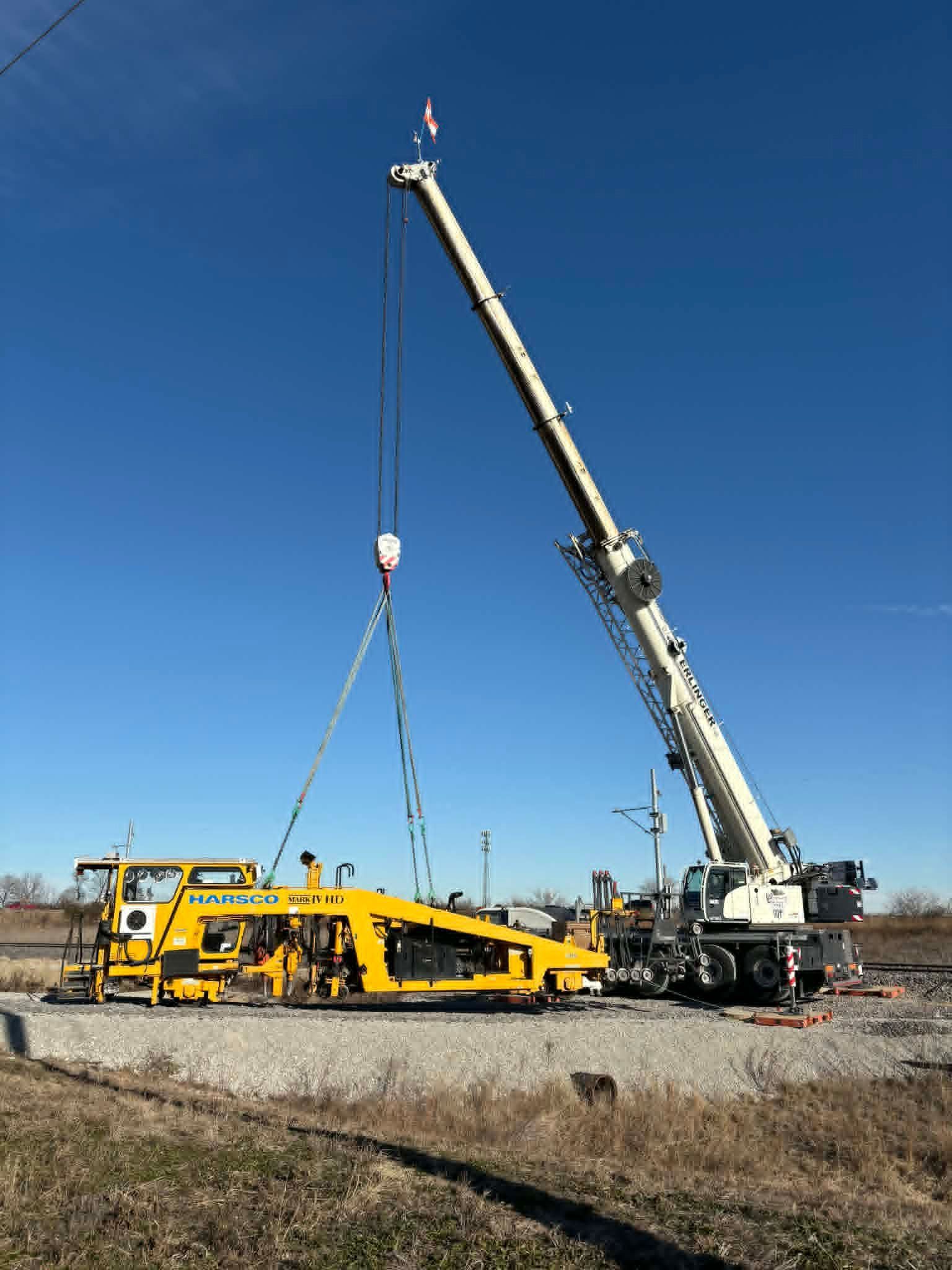 Construction site with yellow excavator, unfinished building, blue sky and sun.