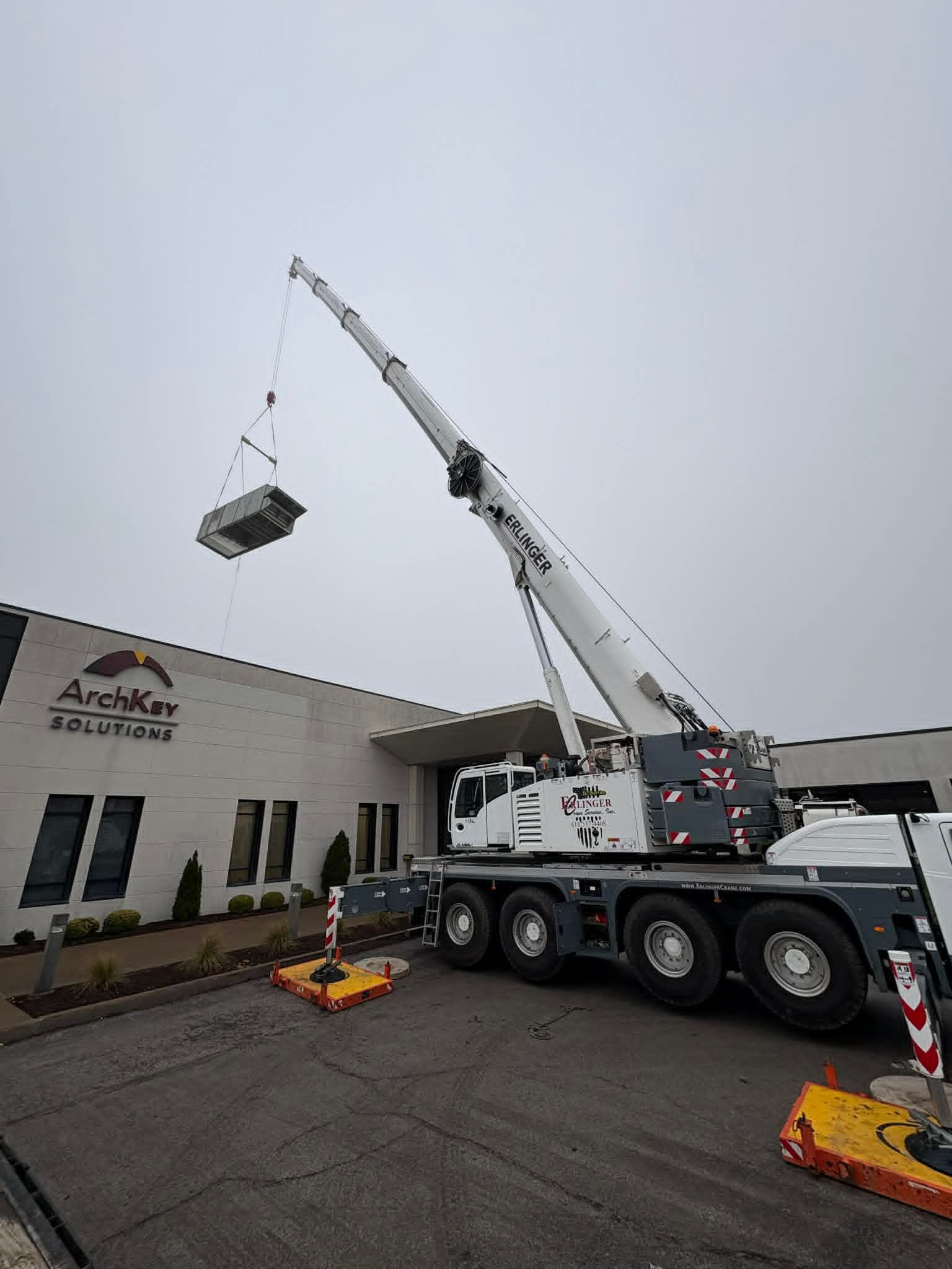 A crane lifting a large, rectangular object near a building with the name