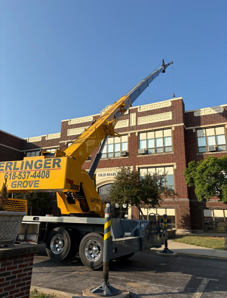 Yellow crane next to a brick building under a clear blue sky.