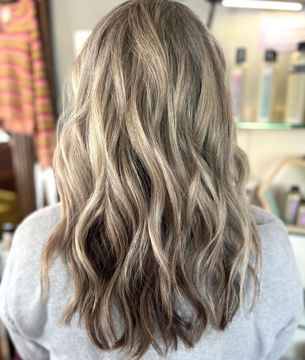 a woman with long blonde hair is wearing a grey shirt