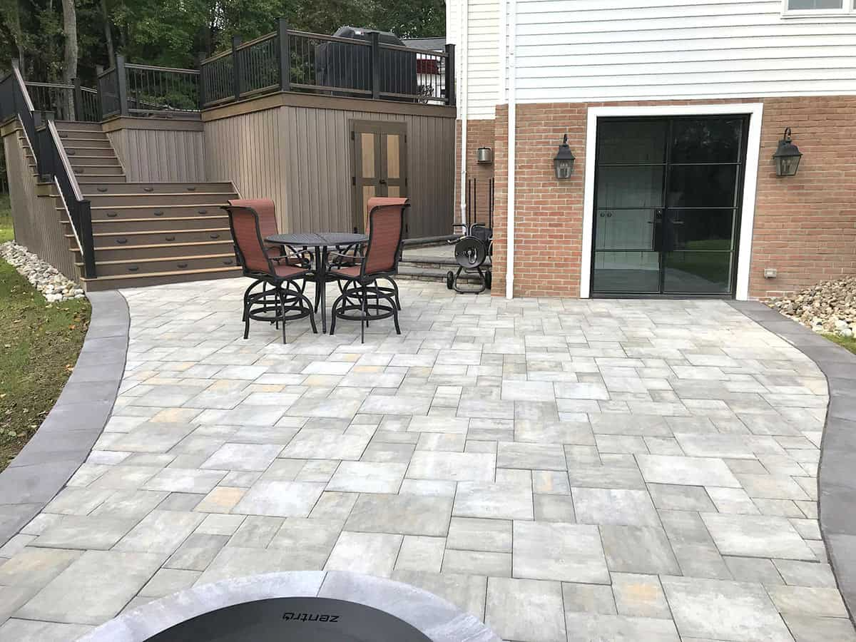 Stone patio with seating, fire pit, stairs, and building with a large glass door.