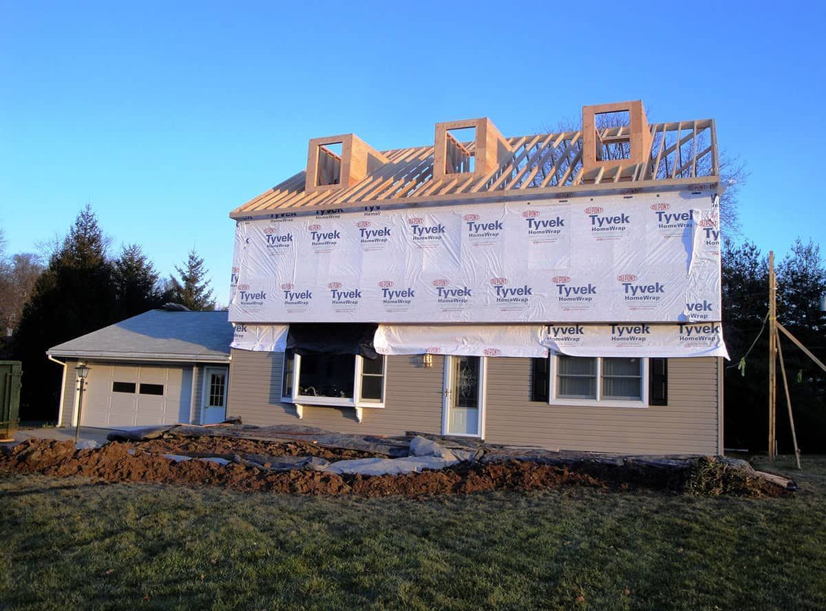 House under construction with attached garage; blue sky.