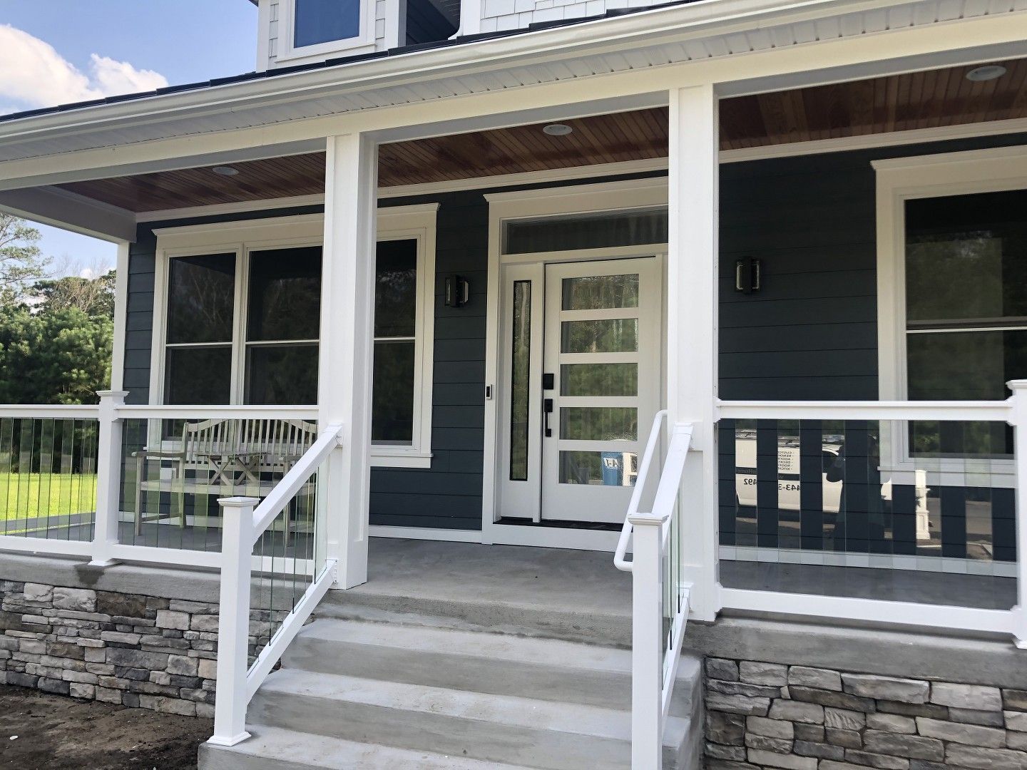 The front porch of a house with a white railing and stairs leading up to it.