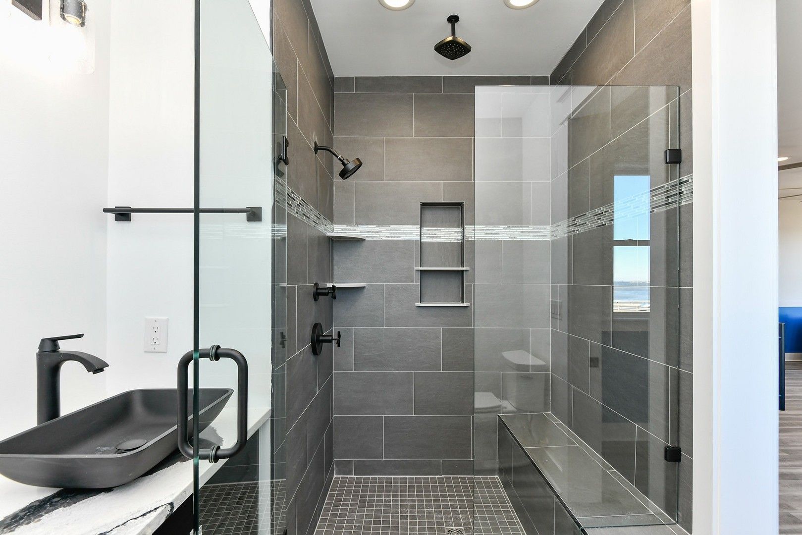 A bathroom with a walk in shower and a sink.