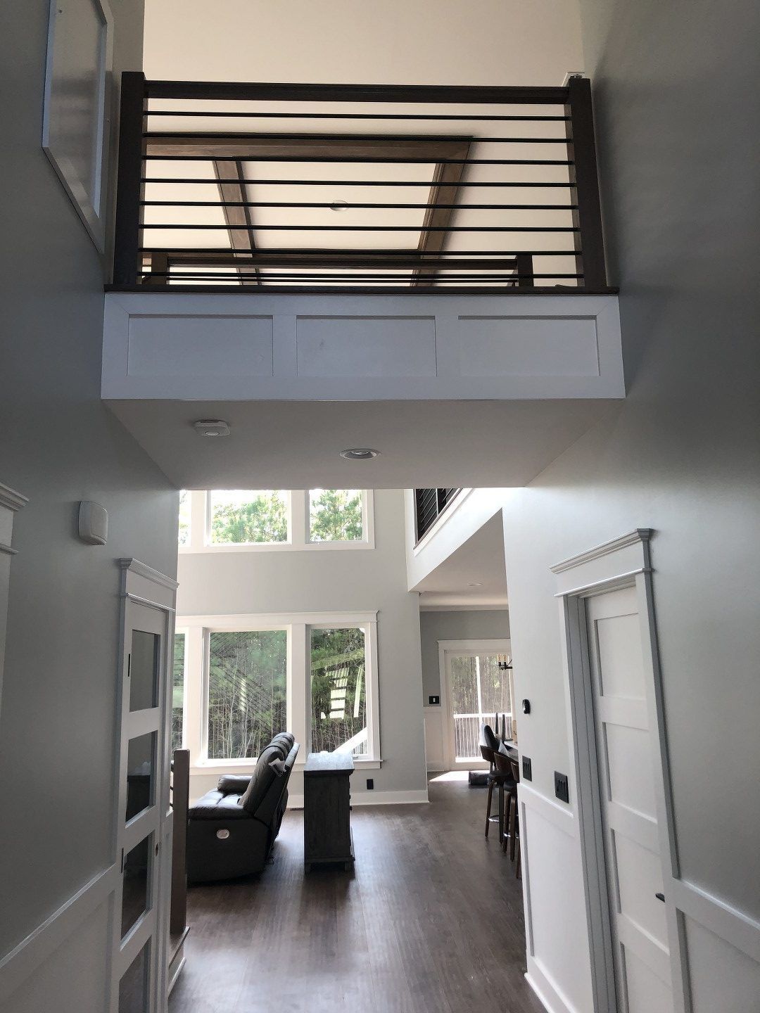 A hallway leading to a living room with a balcony.