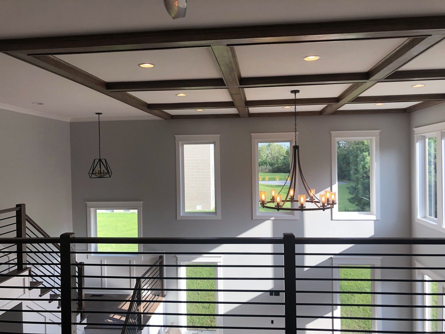 A large room with a balcony and stairs and a chandelier hanging from the ceiling.