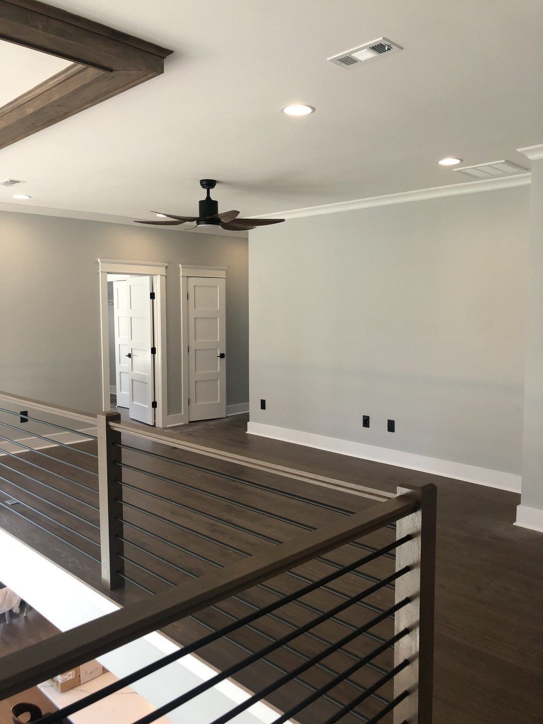 An empty room with a ceiling fan and a railing.