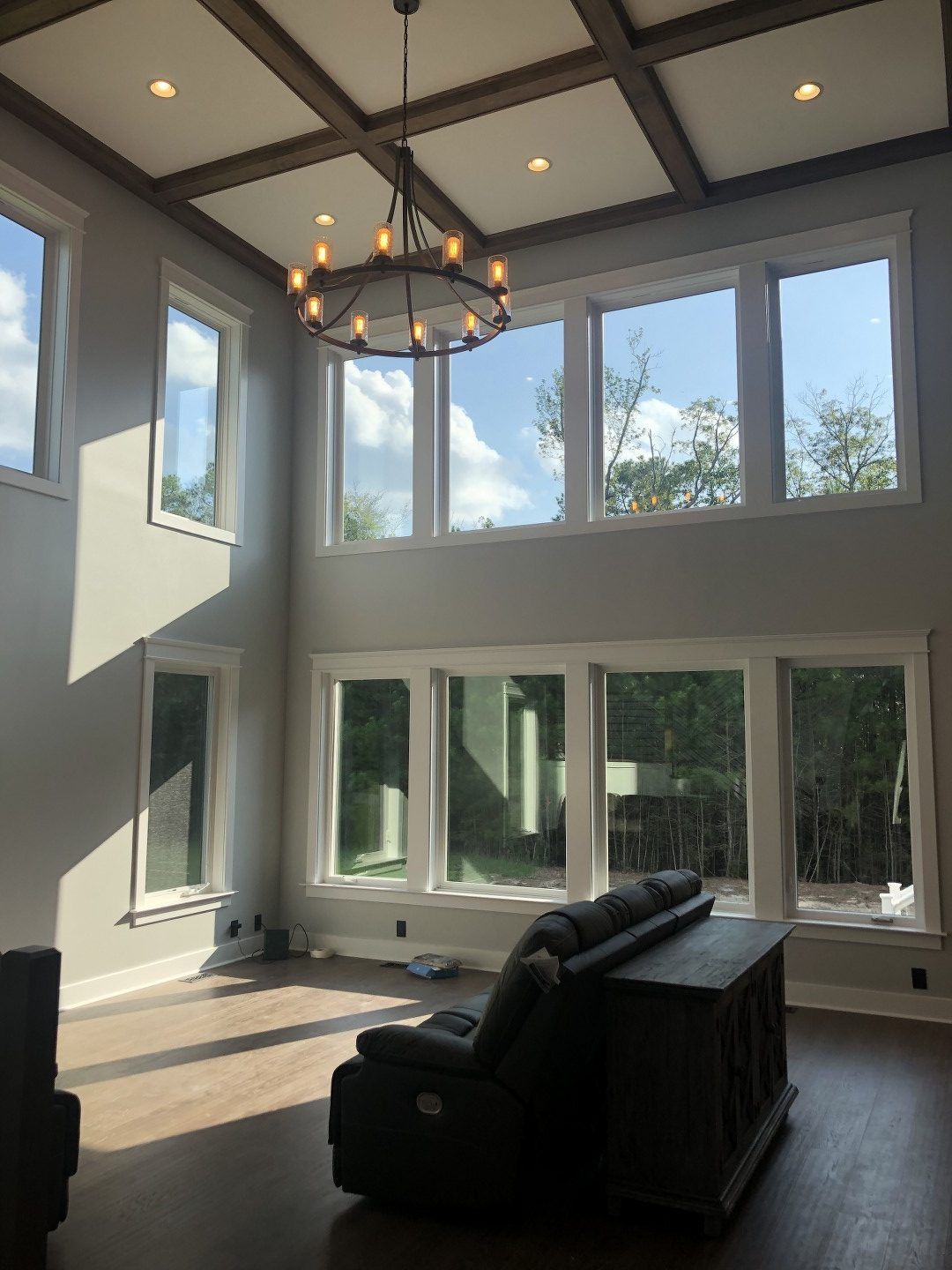A living room with a lot of windows and a chandelier hanging from the ceiling.