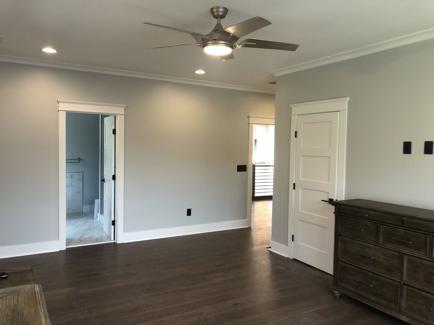 An empty room with a ceiling fan and a dresser