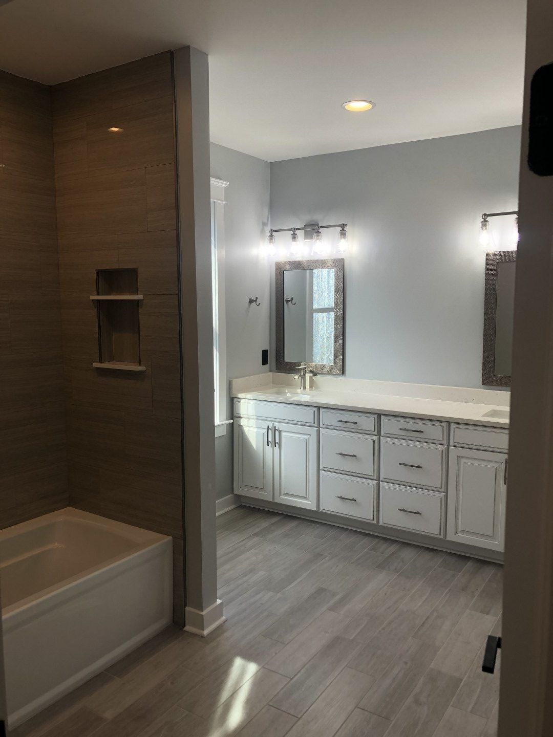 A bathroom with a tub , sink , mirror and shower.
