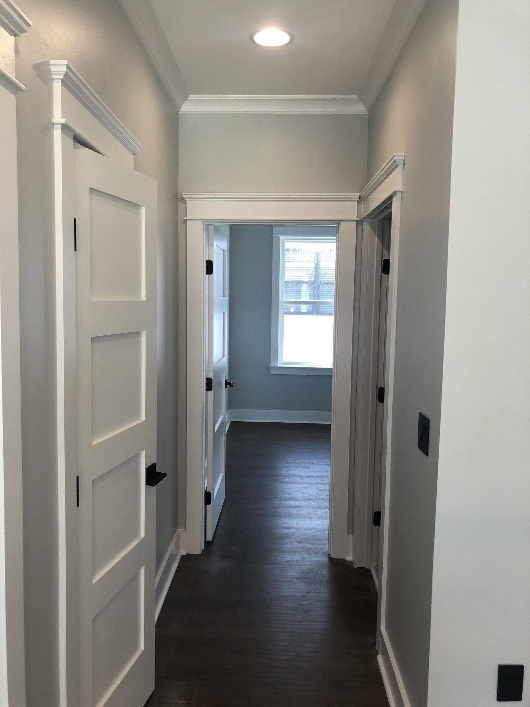 A hallway with white doors leading to a bedroom
