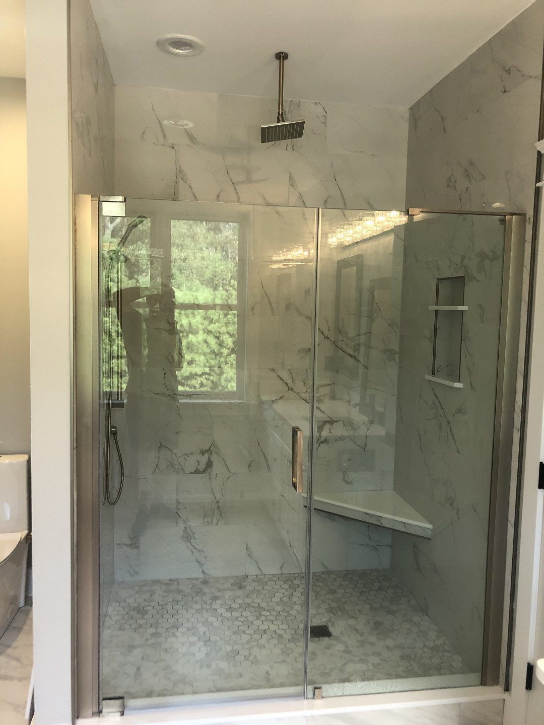 A bathroom with a walk in shower with a glass door.