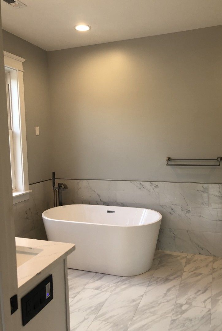 A bathroom with a bathtub , sink , and window.