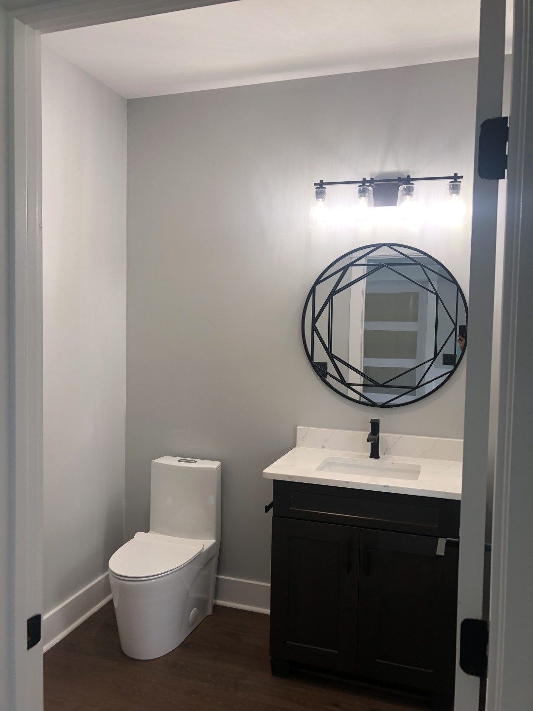 A bathroom with a toilet , sink and mirror.