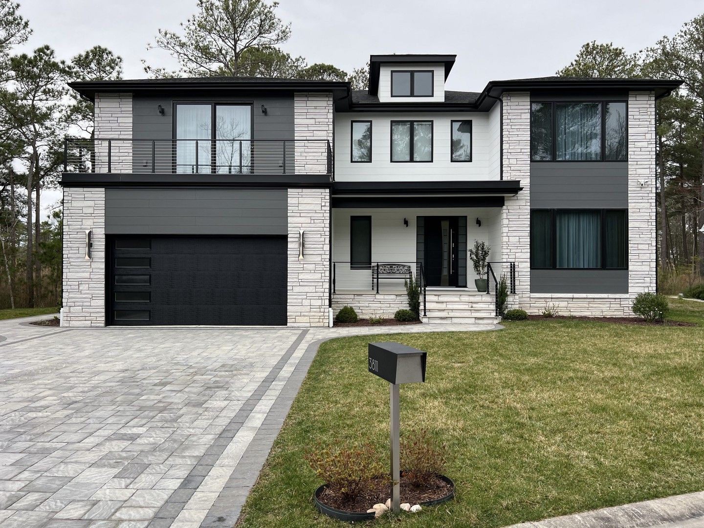 A large house with a black garage door and a mailbox in front of it.