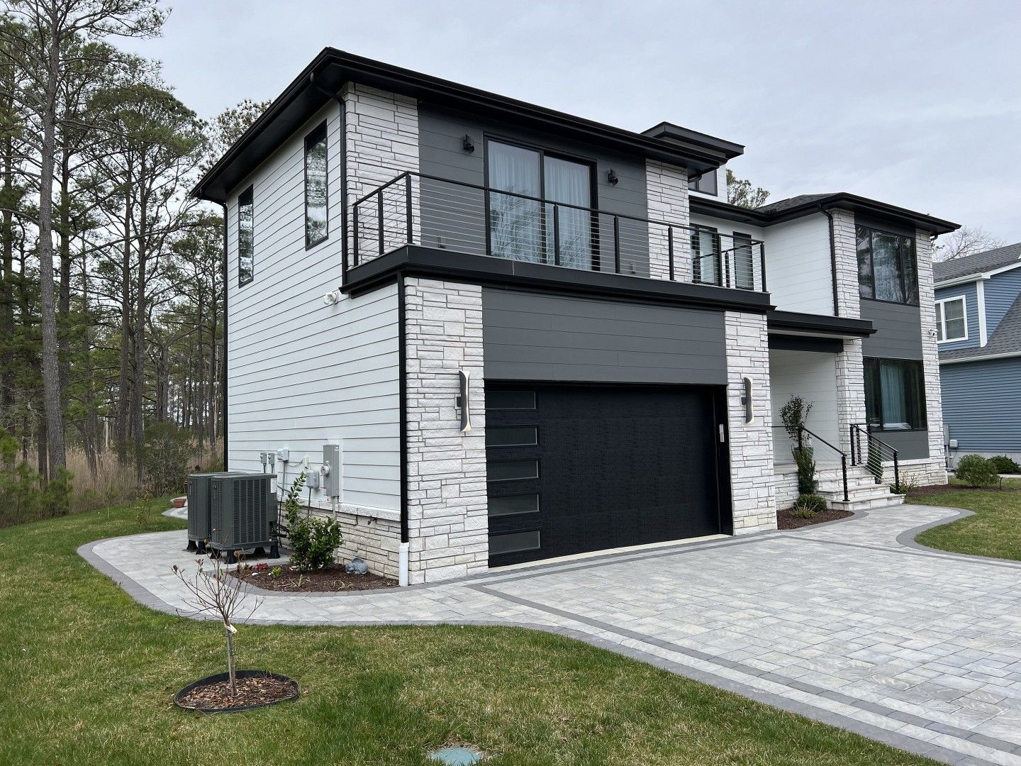 A modern house with a black garage door and a balcony.