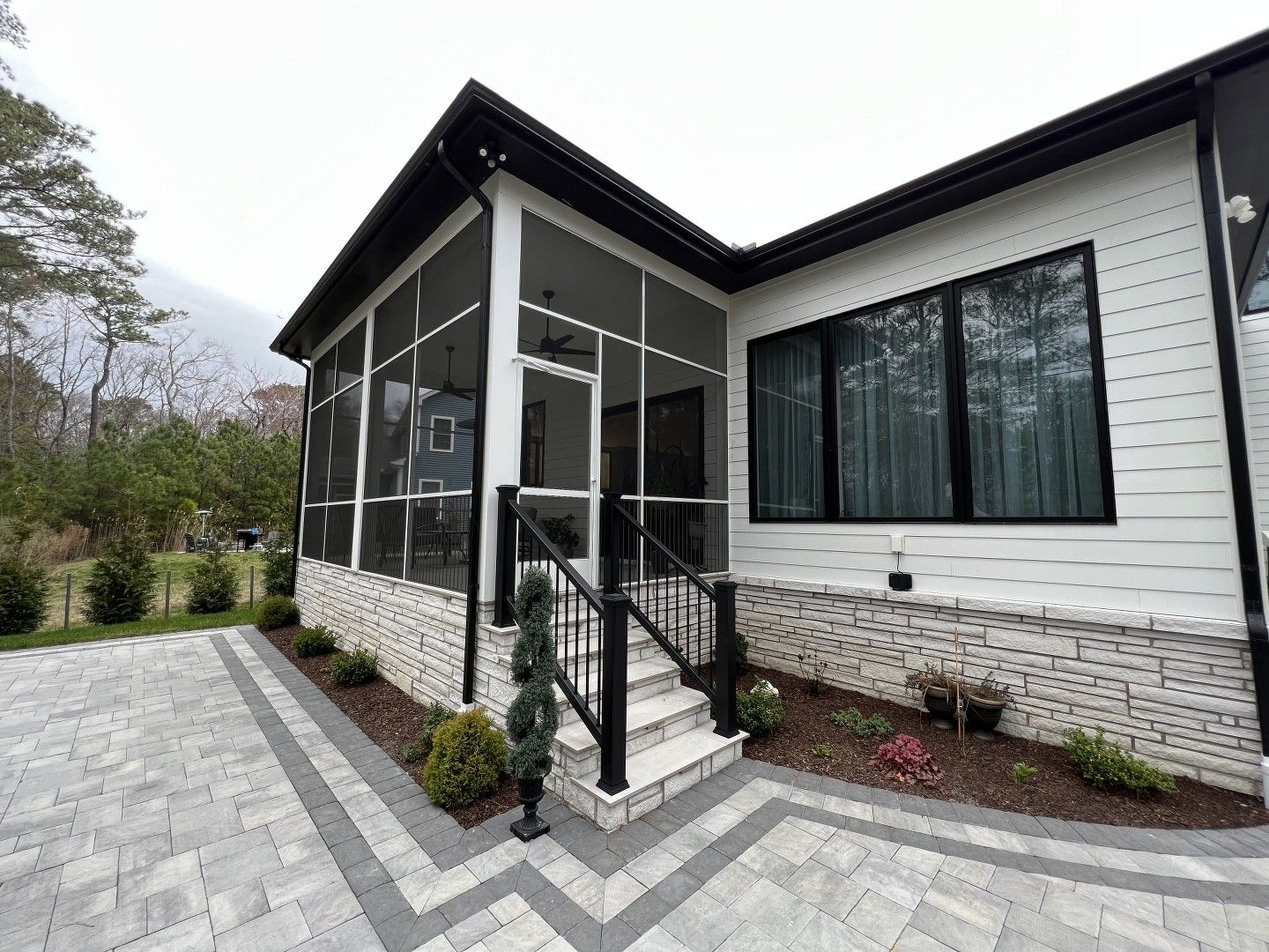 A white house with a screened in porch and stairs.