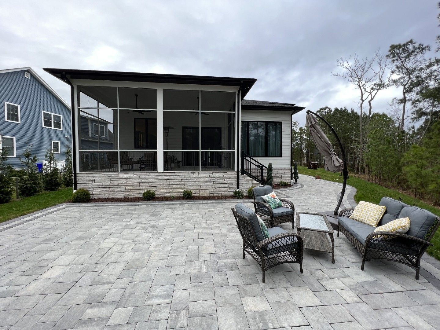 A house with a screened in porch and patio furniture in front of it.
