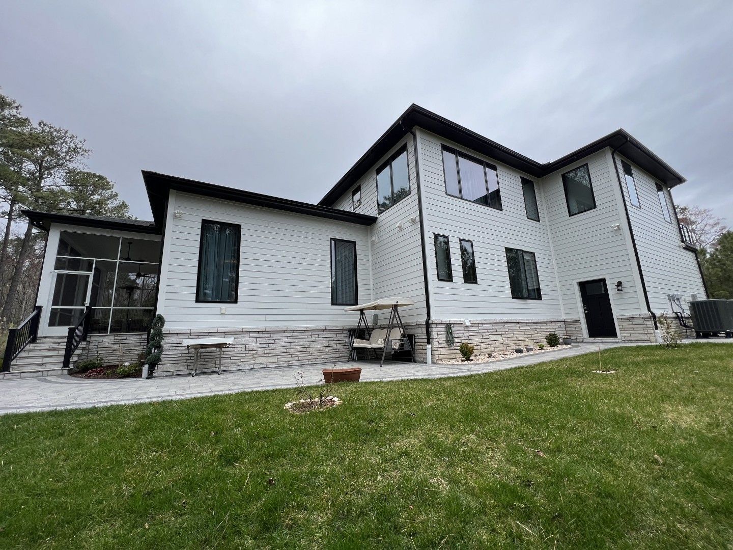 A large white house with a lot of windows is sitting on top of a lush green lawn.