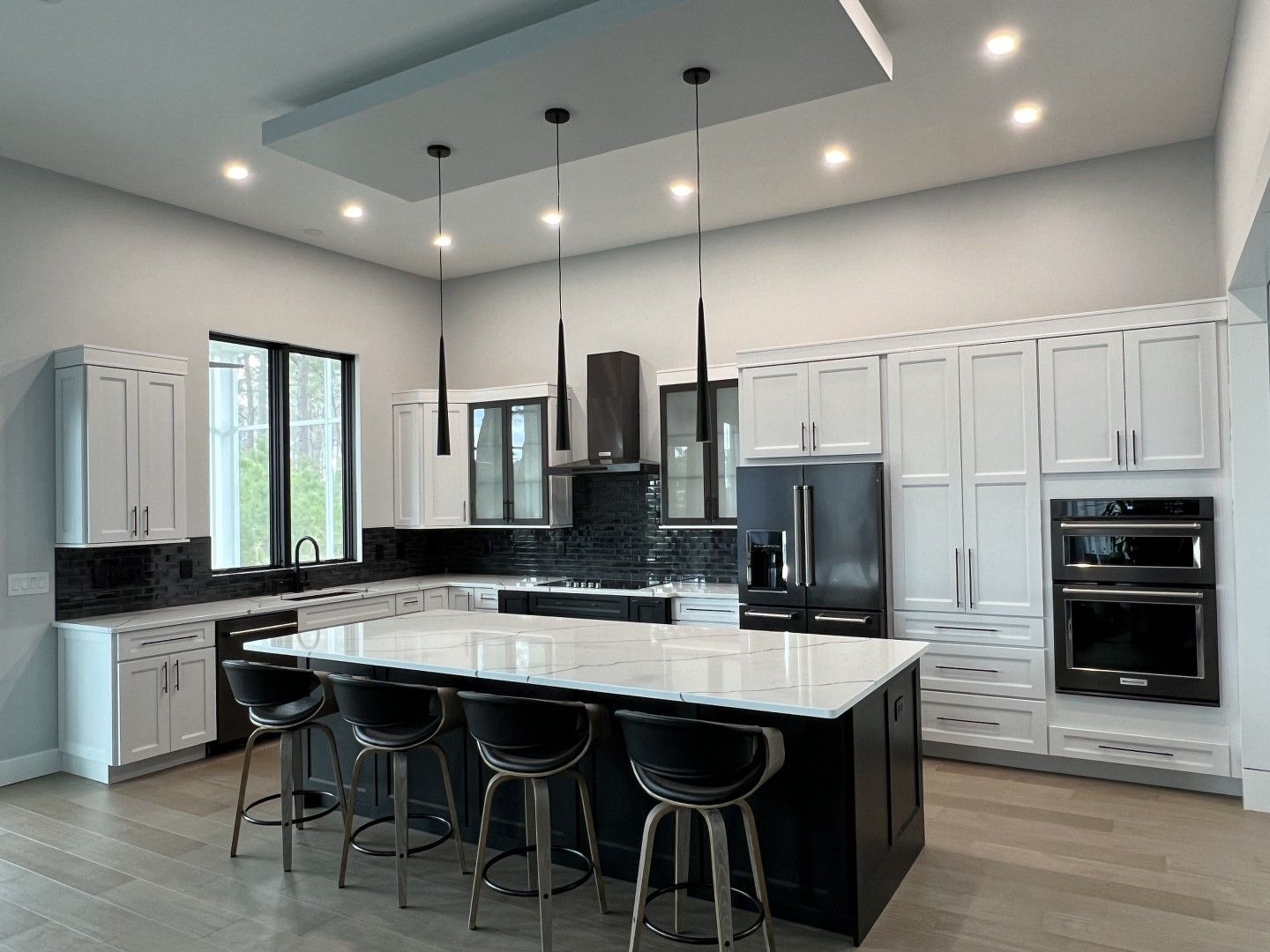 A kitchen with white cabinets and black appliances and a large island.